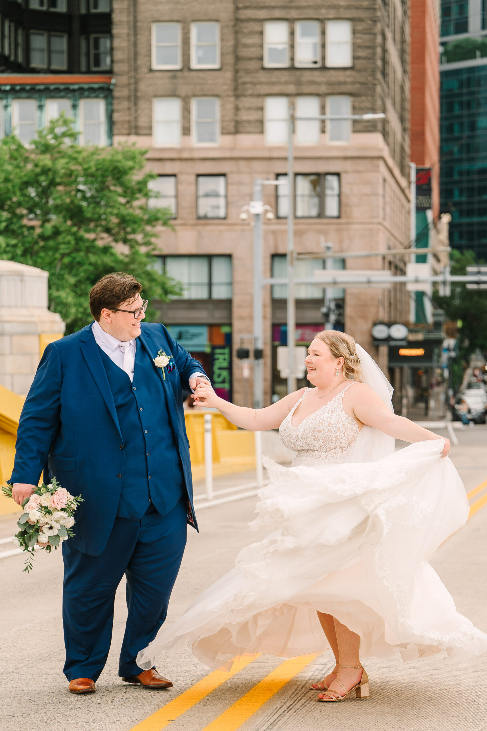 Wedding couple dancing in the street in front of the Renaissance Hotel Pittsburgh, historic architecture and natural light creating an elegant portrait