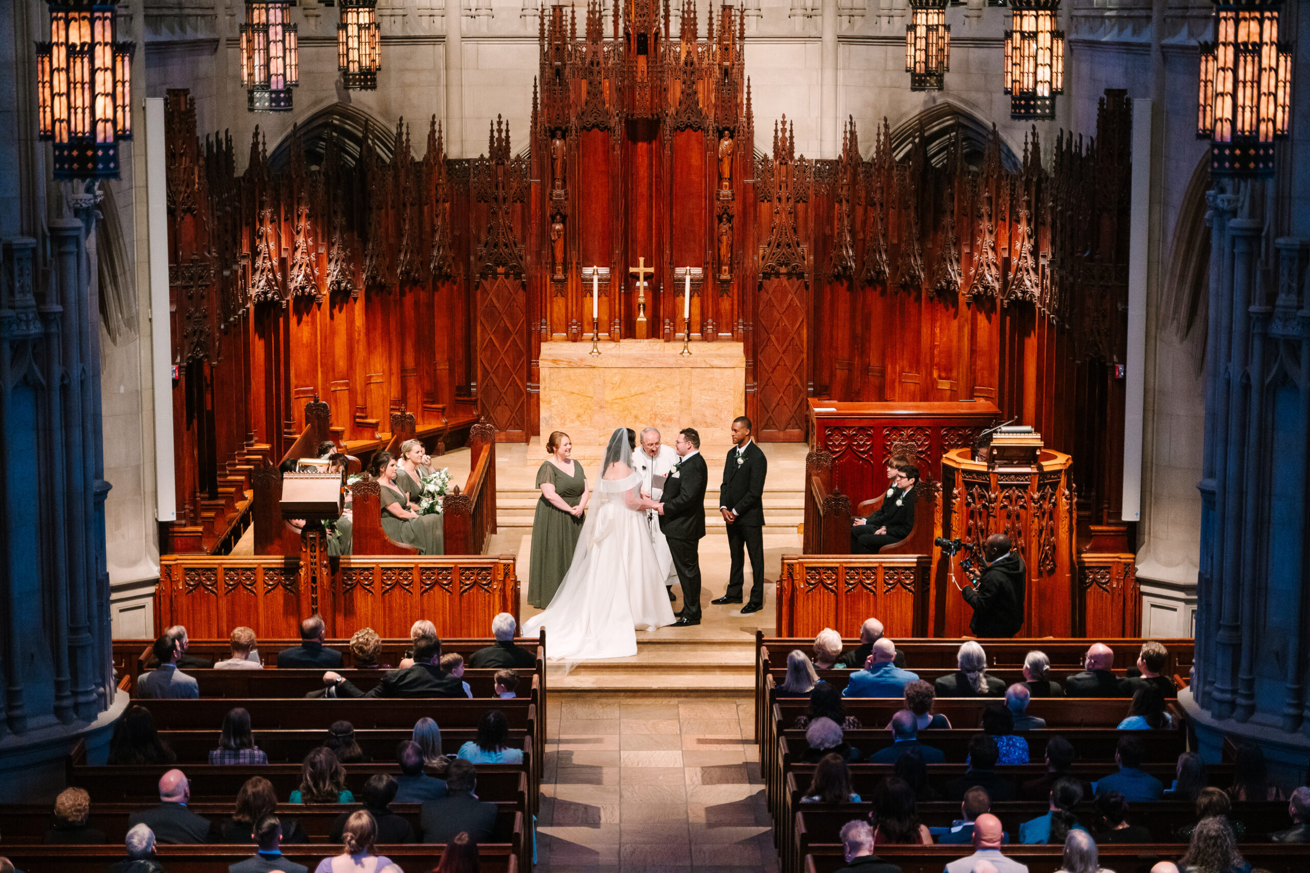 Newlyweds hold hands at the altar of Heinz Chapel, surrounded by beautiful gothic architecture