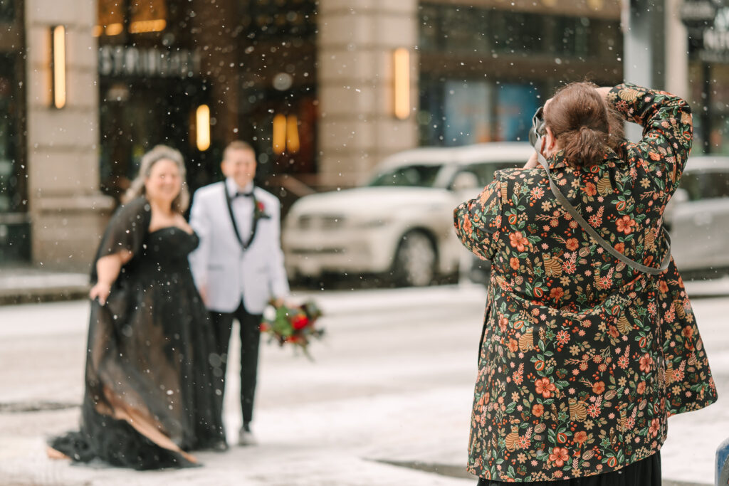 Dawn photographing a couple as they walk through the snow in downtown Pittsburgh to head to their wedding.